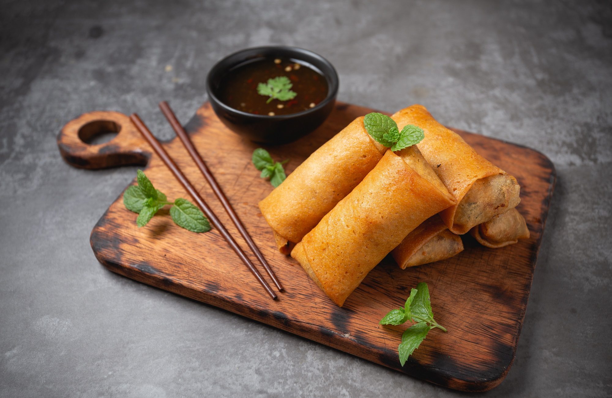 Fried spring rolls on cutting board.