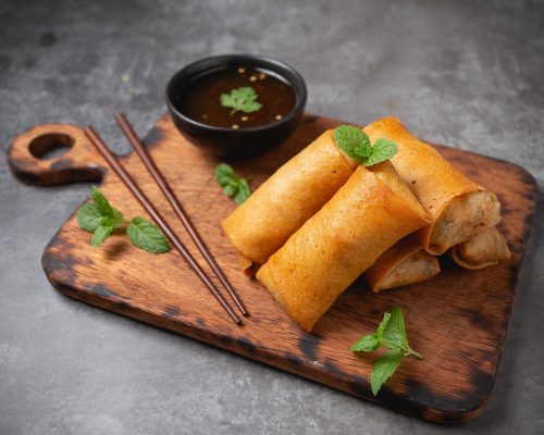 Fried spring rolls on cutting board.
